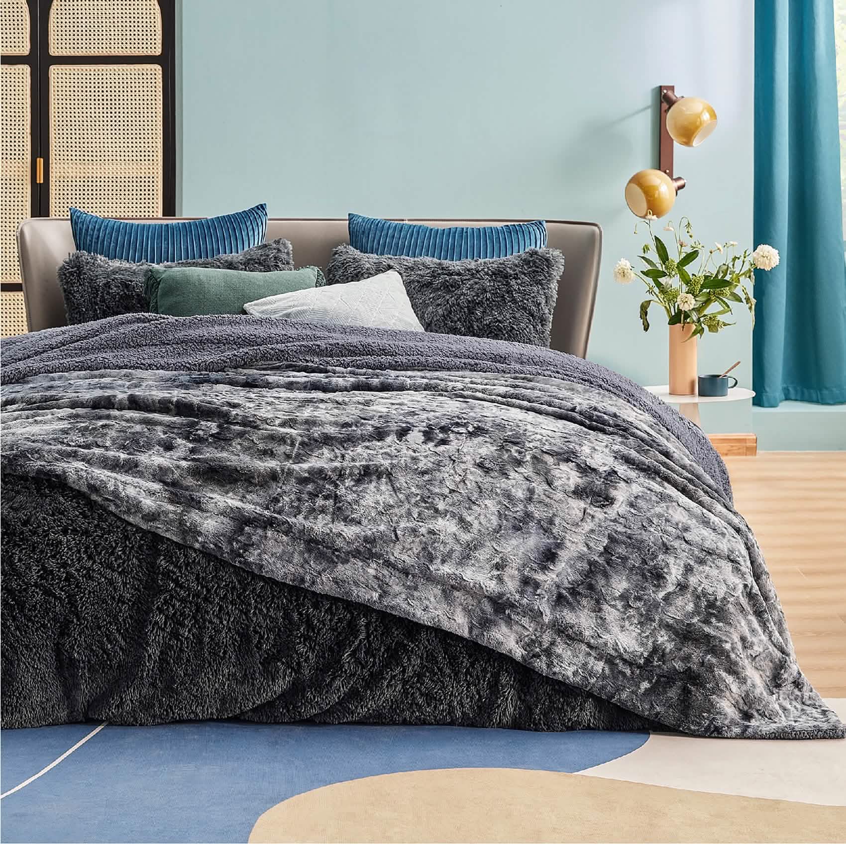 Dark grey reversible GentleSoft Faux Fur Sherpa blanket draped on a bed, showcasing plush texture and cozy feel.