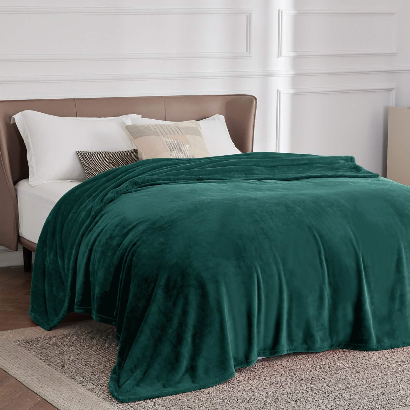 Forest green GentleSoft 300gsm flannel fleece blanket draped on a bed, showcasing plush velvety texture and cozy feel.