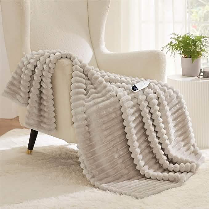 Light gray textured flannel heated blanket draped over armchair with white controller showing heat level.