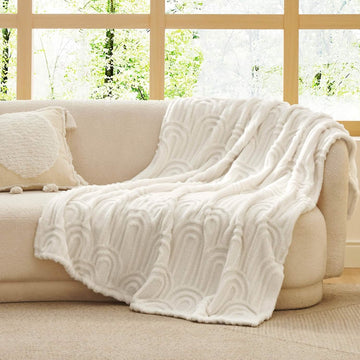 GentleSoft Arch Sherpa Fleece Blanket draped on a cream sofa with embossed arch pattern, showcasing plush texture and style.