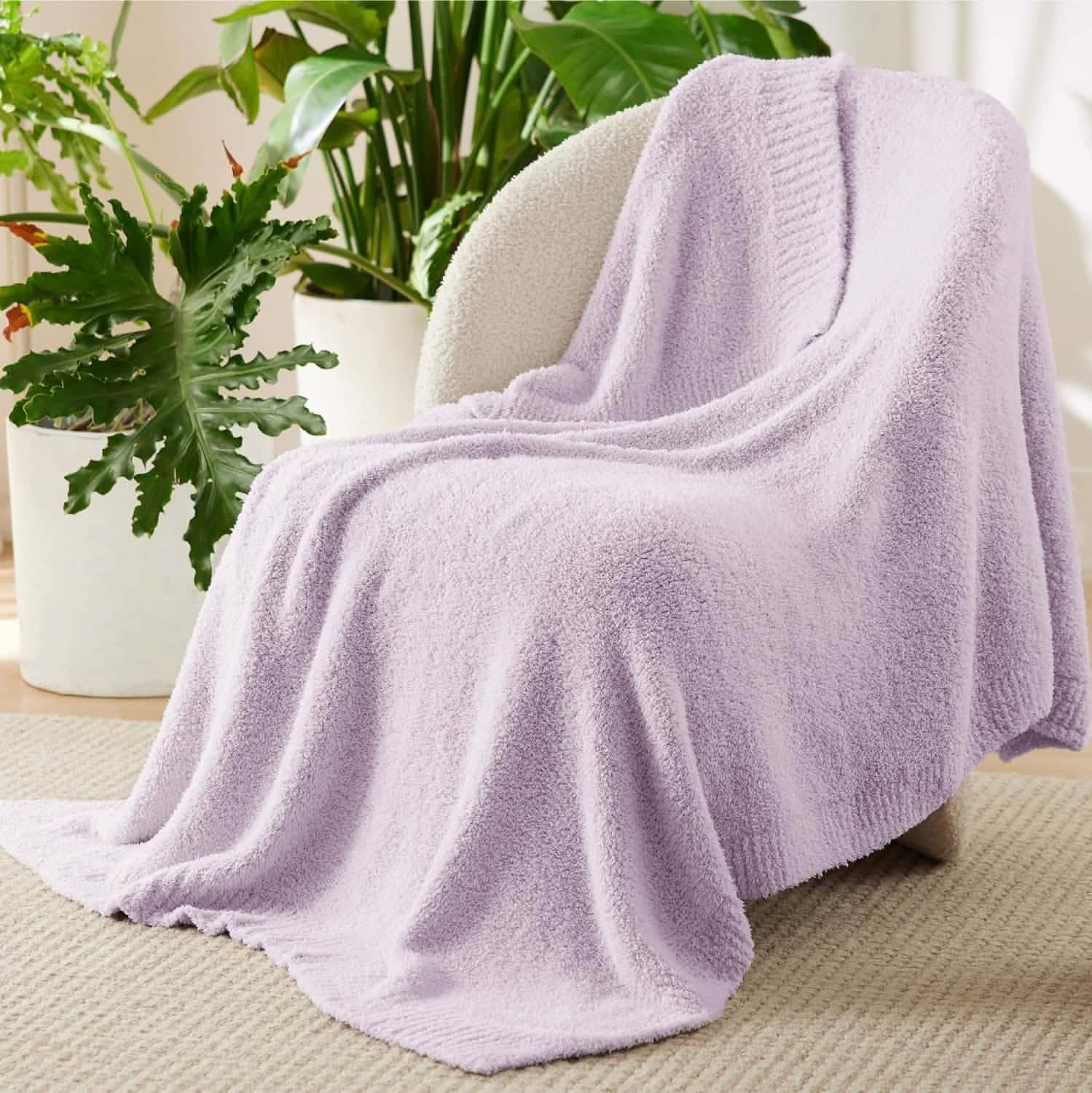 GentleSoft Feather Yarn Throw Blanket in light lavender draped over a cream chair, showcasing its plush texture.